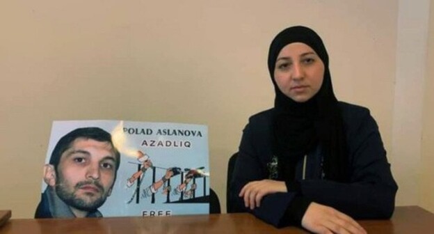 Гюльмира Асланова возле плаката с портретом Полада Асланова. Фото https://www.turan.az/ext/news/2020/12/free/Social/en/131347.htm Гюльмира Асланова возле плаката с портретом Полада Асланова. Фото https://www.turan.az/ext/news/2020/12/free/Social/en/131347.htm