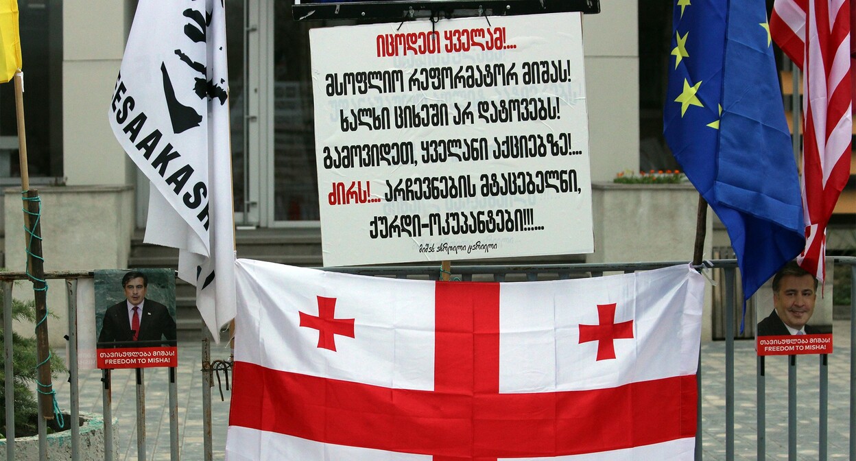 Флаг Грузии и плакат с надписью: "Знайте все! Всемирного реформатора Мишу! Народ не оставит в тюрьме! Выйдете все на акции!.. Долой!.. Похитителей выборов, воров-оккупантов!!!...". Тбилиси, 7 ноября 2021 г. Фото Инны Кукуджановой для "Кавказского узла" Флаг Грузии и плакат с надписью: "Знайте все! Всемирного реформатора Мишу! Народ не оставит в тюрьме! Выйдете все на акции!.. Долой!.. Похитителей выборов, воров-оккупантов!!!...". Тбилиси, 7 ноября 2021 г. Фото Инны Кукуджановой для "Кавказского узла"