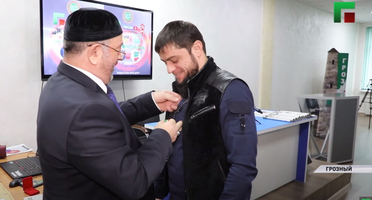 Вручение министру печати Чечни Ахмеду Дудаеву (справа) медали за защиту прав человека. Cкриншот видео ЧГТРК "Грозный" https://www.youtube.com/watch?v=RSCzvy_pPPk Вручение министру печати Чечни Ахмеду Дудаеву (справа) медали за защиту прав человека. Cкриншот видео ЧГТРК "Грозный" https://www.youtube.com/watch?v=RSCzvy_pPPk