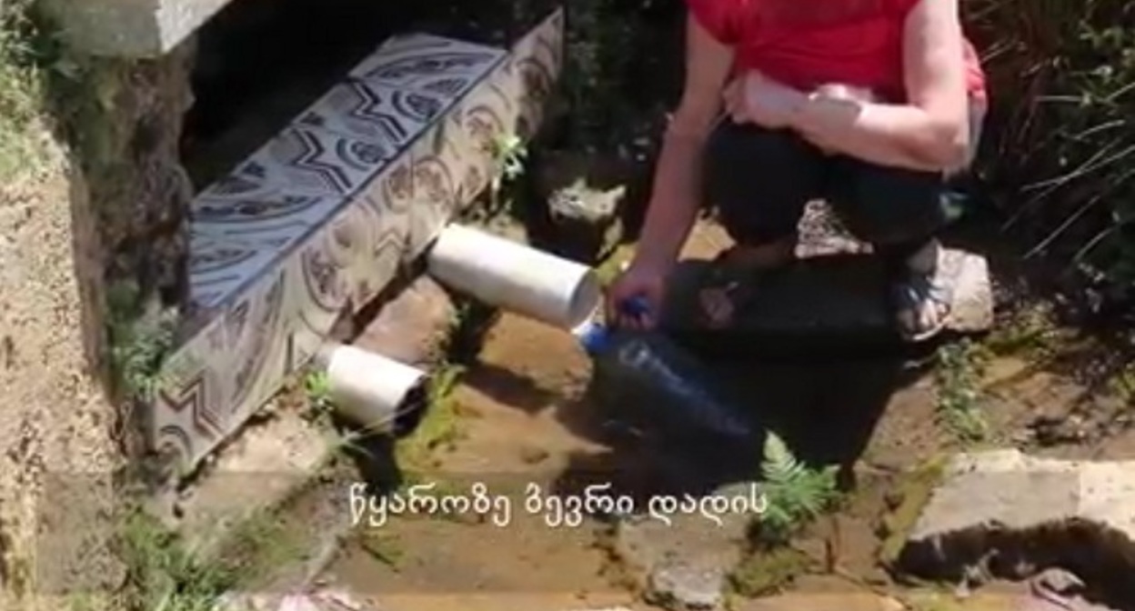 Жительница села Очхамури набирает воду из источника. Стопкадр из видео на странице https://batumelebi.netgazeti.ge/news/416076/ Жительница села Очхамури набирает воду из источника. Стопкадр из видео на странице https://batumelebi.netgazeti.ge/news/416076/