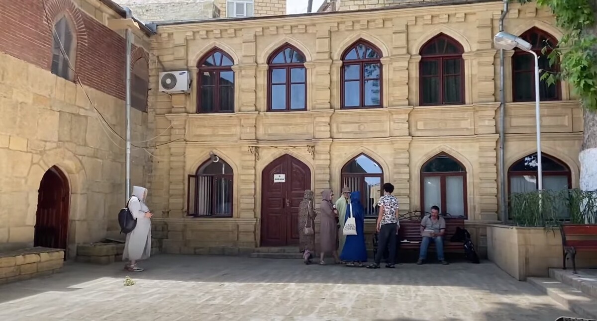 Туристы во дворе мечети в Дербенте. Стоп-кадр из видео https://www.youtube.com/watch?v=1rUg3LrF6kQ Туристы во дворе мечети в Дербенте. Стоп-кадр из видео https://www.youtube.com/watch?v=1rUg3LrF6kQ