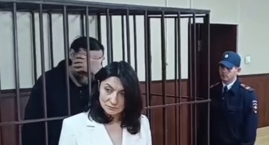 Замглавы Дирекции парков и скверов Махачкалы закрывает лицо рукой в клетке суда. Кадр видео Объединенной пресс-службы судов Дагестана https://t.me/Femida_Dagestana/124