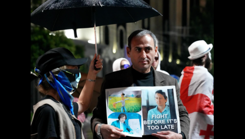 Участник акции с плакатом о Мзие Амаглобели. Скриншот фото Publika от 05.07.25, https://www.facebook.com/photo?fbid=1489125559153656&set=pcb.1489125722486973 (деятельность компании Meta, владеющей соцсетью, запрещена в России).