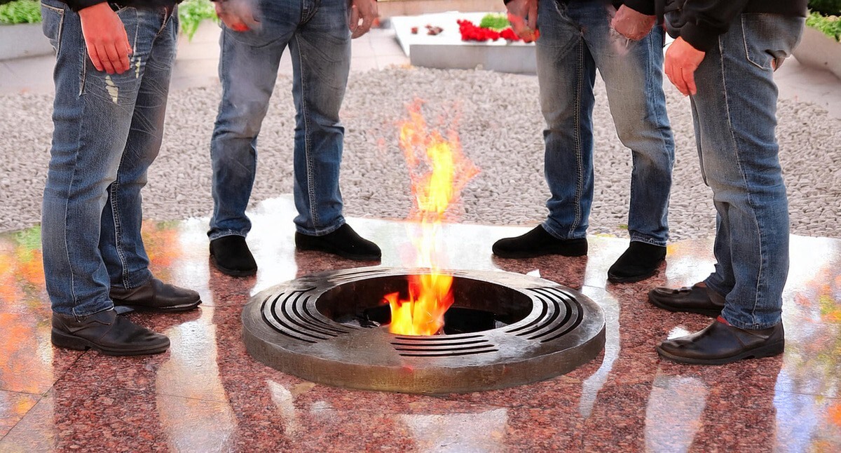 Мужчины стоят у Вечного огня. Иллюстрация создана "Кавказским узлом" с помощью ИИ в программе Photoshop