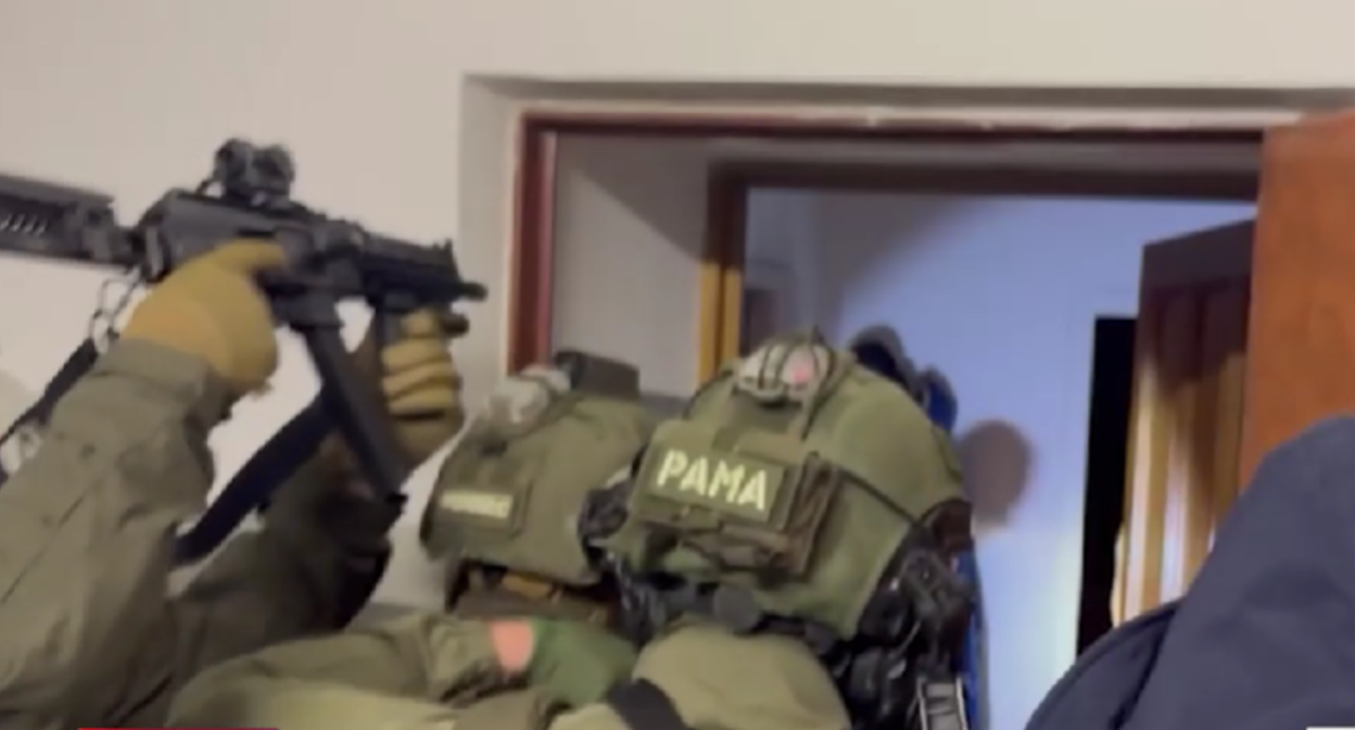 Силовики входят в квартиру одного из задержанных. Стоп-кадр видео https://t.me/kommersant/98586 от 30.12.25.