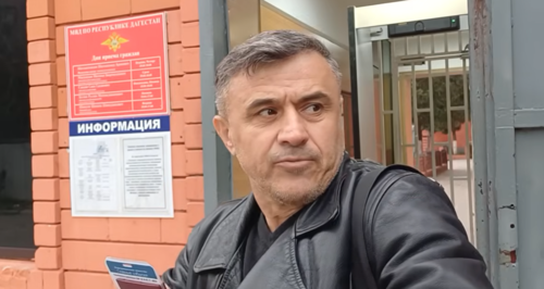 Асхабали Алибеков у отдела полиции в Хасавюрте. Сто-кадр видео из YouTube-канала "Дикий десантник" от 11.04.26, https://www.youtube.com/watch?v=D7oP2PtLQkE Асхабали Алибеков у отдела полиции в Хасавюрте. Сто-кадр видео из YouTube-канала "Дикий десантник" от 11.04.26, https://www.youtube.com/watch?v=D7oP2PtLQkE